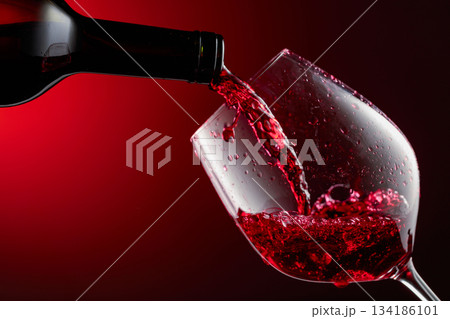 Red wine is poured from a bottle into a glass. Red wine is poured from a bottle into a glass. 134186101