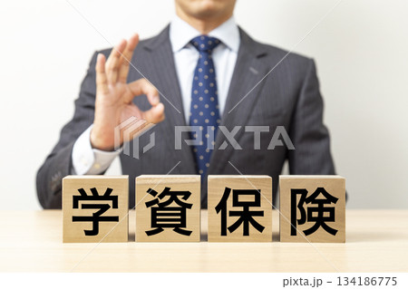 「学資保険」と書かれたブロックとOKポーズをするビジネスマン 134186775