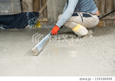 Craftsman Smoothing Fresh Concrete Surface with Hand Tool for Perfect Flooring Finish 134186894