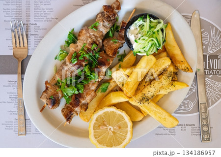 Delicious Greek Souvlaki Grilled Meat Skewer with Fries, Lemon, and Tzatziki Sauce Delicious Greek Souvlaki Grilled Meat Skewer with Fries, Lemon, and Tzatziki Sauce 134186957