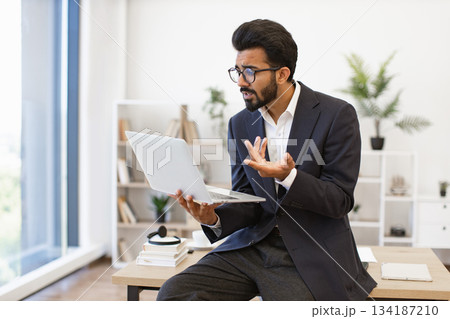 An Arabian businessman gestures while using a laptop during a video conference in his office 134187210