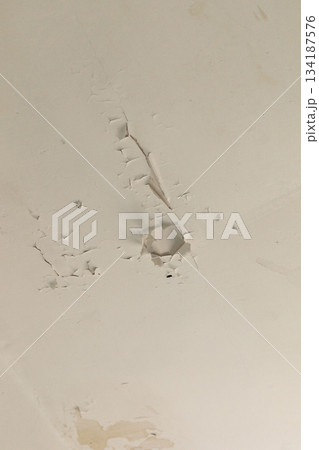 Ceiling of an old house displays noticeable cracks and peeling paint, indicating long-term neglect and deterioration. The surrounding environment feels neglected and abandoned 134187576