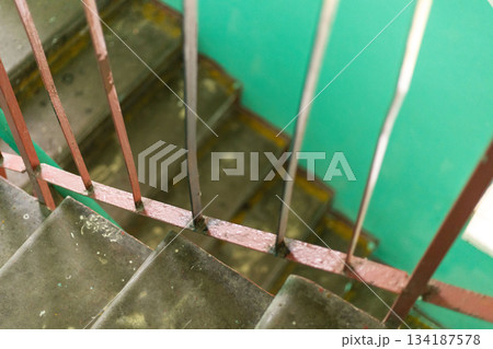 Stairs inside an old house display peeling paint and worn surfaces, surrounded by a vivid green wall. The atmosphere reflects years of wear and tear, emphasizing its condition Stairs inside an old house display peeling paint and worn surfaces, surrounded by a vivid green wall. The atmosphere reflects years of wear and tear, emphasizing its condition 134187578