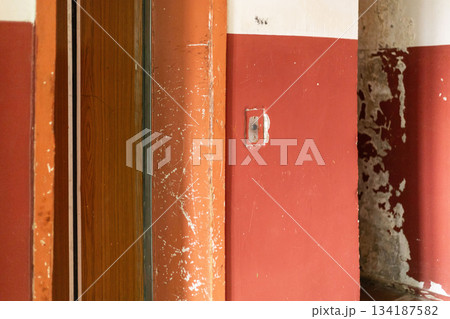 The interior of an old house reveals walls in deteriorating condition, marked by peeling paint and wear. The space conveys a sense of abandonment and age, highlighting the need for repairs The interior of an old house reveals walls in deteriorating condition, marked by peeling paint and wear. The space conveys a sense of abandonment and age, highlighting the need for repairs 134187582