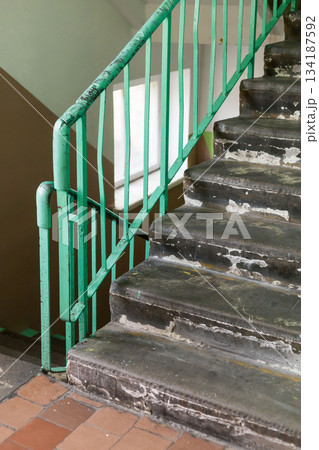 An old staircase with worn steps and rusty railings reflects years of neglect in a once vibrant home. The faded paint and chipped edges tell stories of the past and forgotten memories An old staircase with worn steps and rusty railings reflects years of neglect in a once vibrant home. The faded paint and chipped edges tell stories of the past and forgotten memories 134187592