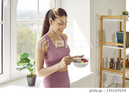 Sporty young woman in sportswear eating healthy food after working out at home. Sporty young woman in sportswear eating healthy food after working out at home. 134187634
