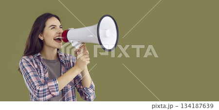 Happy young woman shouting into megaphone making announcement 134187639