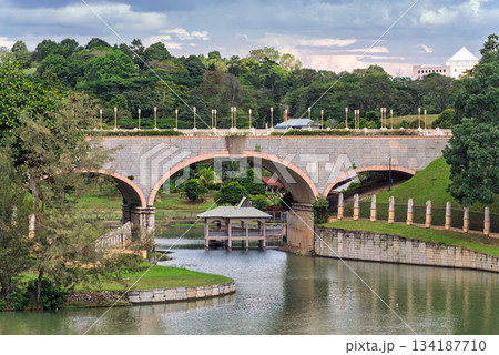 Seri Gemilang Bridge, a stone arch bridge, spanning across water with surrounding greenery in Putrajaya, Malaysia. 134187710