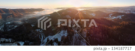 Aerial view, panoramic image majestic mountain landscape at sunrise. Sun's rays cast warm glow over the peaks and valleys. Mist clings to valleys, giving scene mystical, ethereal quality. 134187717