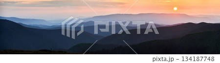 Panoramic view of tranquil scene at dusk, showcasing layers of rolling hills bathed in soft blue hues, with fading light of sunset casting gentle orange and pink glow over distant horizon. Panoramic view of tranquil scene at dusk, showcasing layers of rolling hills bathed in soft blue hues, with fading light of sunset casting gentle orange and pink glow over distant horizon. 134187748