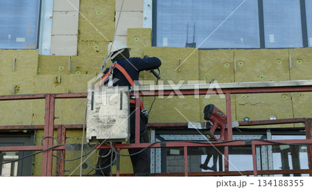 Construction site with a worker standing and supervising the unfinished building 134188355