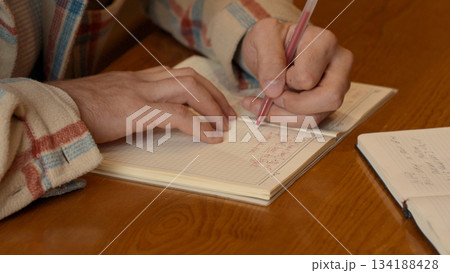 Close-up on the hands of a man writing in a book or filling out a form 134188428