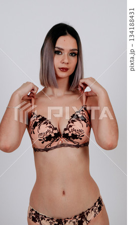 Sensual woman in floral lace bra, hands covering chest, shy expression 134188431