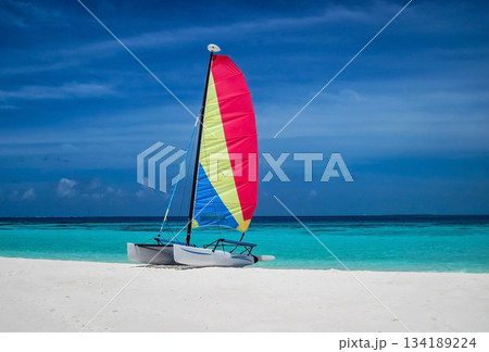 Sailing boat with colorful sail on sandy beach near the ocean bay. Sailing boat with colorful sail on sandy beach near the ocean bay. 134189224