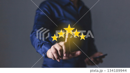 Review Customer, Young Man with smartphone hand touching five star to review and give 5 stars with very good results in service, Good review 5 star rating choice feedback Review Customer, Young Man with smartphone hand touching five star to review and give 5 stars with very good results in service, Good review 5 star rating choice feedback 134189944