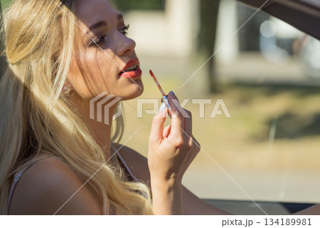 Woman applying lip gloss in car 134189981