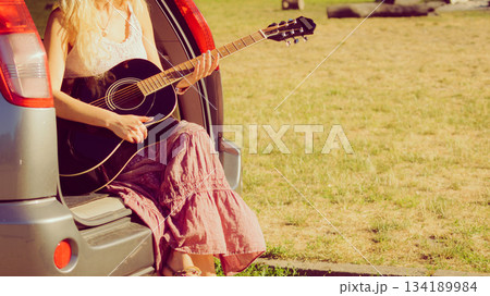 Hippie woman playing guitar in van car Hippie woman playing guitar in van car 134189984