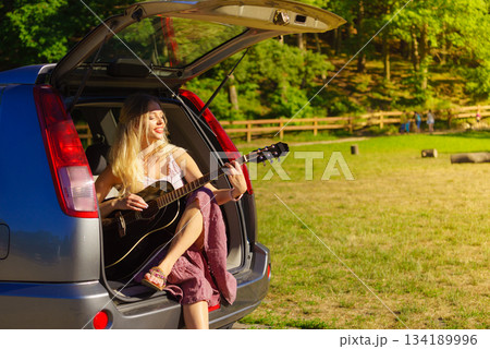 Girl with guitar on hatchback car Girl with guitar on hatchback car 134189996