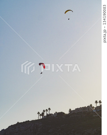 Paragliders flying in blue sky. Paragliders flying in blue sky. 134190083