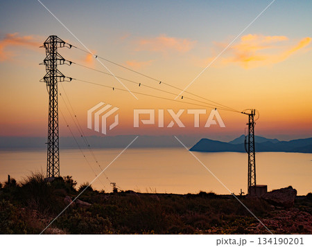 High voltage towers on coast at sunset High voltage towers on coast at sunset 134190201
