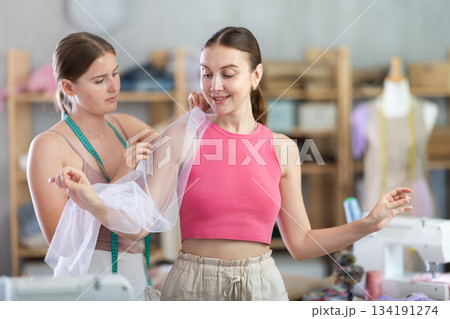 Young female seamstress adjusting clothes on adult woman 134191274