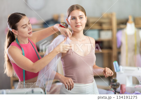 Adult female seamstress adjusting clothes on young woman 134191275