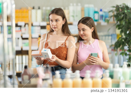 young woman with her daughter choosing pills at the pharmacy 134191301