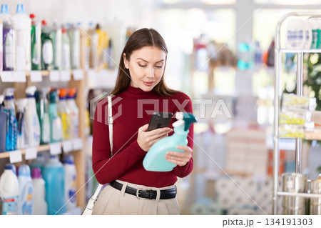 Young woman scanning qr code for cleaning spray Young woman scanning qr code for cleaning spray 134191303