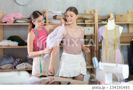 Adult female seamstress adjusting clothes on young woman 134191493