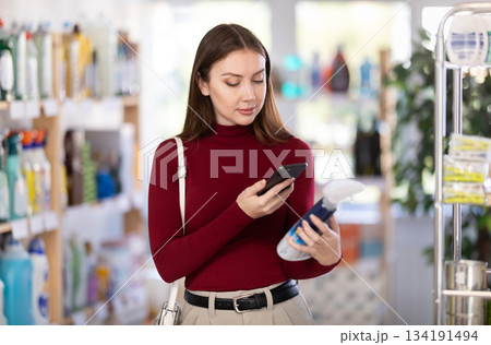 Young woman scanning qr code for cleaning spray Young woman scanning qr code for cleaning spray 134191494