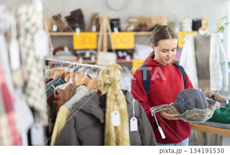 Positive teenage girl choosing fur hat in clothing store 134191530