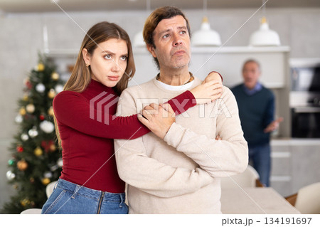 Sad couple listens to their elderly father scream and swear while celebrating Christmas. Family quarrel 134191697