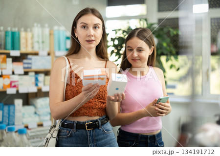 Woman with daughter choosing pills in pharmacy 134191712
