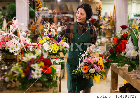 Female florist in apron holding bouquet at flower shop Female florist in apron holding bouquet at flower shop 134191728