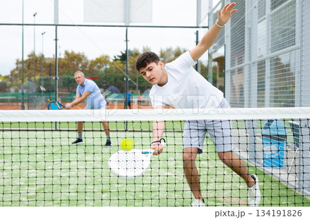 Young focused guy playing paddle tennis outdoors Young focused guy playing paddle tennis outdoors 134191826