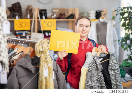 Teenage girl holding sale banner in clothing store Teenage girl holding sale banner in clothing store 134191885