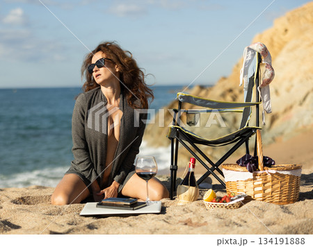 Attractive businesswoman kneeling on sandy beach Attractive businesswoman kneeling on sandy beach 134191888