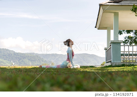 A woman practicing yoga outdoors, soaking up sun while getting her yoga 134192071