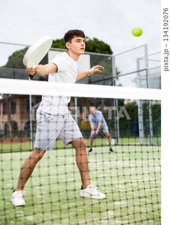 Sporty young guy playing padel on open court Sporty young guy playing padel on open court 134192076