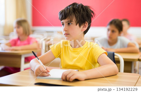 Schoolboy sitting in classroom during lesson in elementary school Schoolboy sitting in classroom during lesson in elementary school 134192229