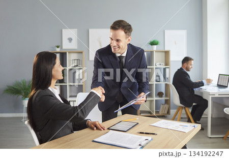 Businessman and Client Shaking Hands in Office for a Positive Deal and Agreement Businessman and Client Shaking Hands in Office for a Positive Deal and Agreement 134192247