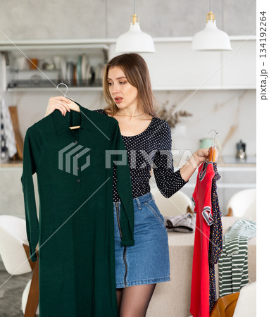 Young upset woman choosing which dress to wear Young upset woman choosing which dress to wear 134192264