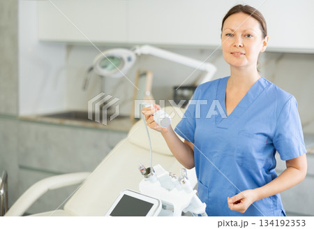 Adult woman cosmetologist posing with cosmetology apparatus Adult woman cosmetologist posing with cosmetology apparatus 134192353
