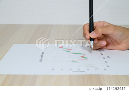 株価チャートとペンを持つ手 134192415