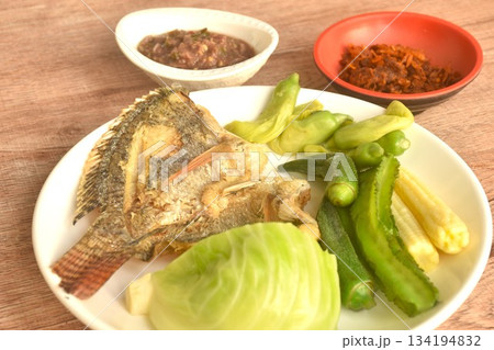 batter fried tilapia fish with boiled vegetable on plate dipping spicy shrimp paste sauce 134194832