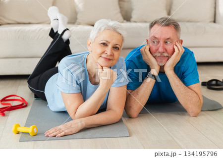 Fitness workout home training. Senior adult mature healthy fit couple resting after sports exercise on yoga mat at home. Mid age old husband wife have training workout. Health care healthy lifestyle Fitness workout home training. Senior adult mature healthy fit couple resting after sports exercise on yoga mat at home. Mid age old husband wife have training workout. Health care healthy lifestyle 134195796