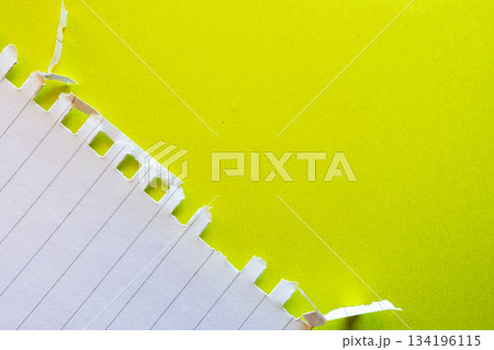 Ripped white paper with lined texture on a bright yellow background. The torn edge creates a contrast between the two colors. 134196115
