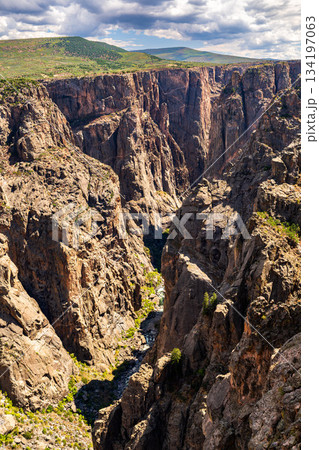 Steep rock walls of Black Canyon of the Gunnison National Park rise above the river in Colorado, USA. Dramatic landscape features dark metamorphic cliffs with pegmatite dikes Steep rock walls of Black Canyon of the Gunnison National Park rise above the river in Colorado, USA. Dramatic landscape features dark metamorphic cliffs with pegmatite dikes 134197063