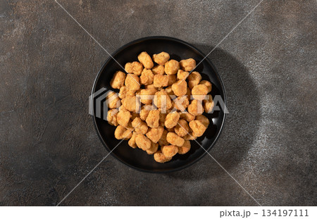 Crispy chicken popcorn bites in black bowl on gray background.Top view.Concept snack fast food menus Crispy chicken popcorn bites in black bowl on gray background.Top view.Concept snack fast food menus 134197111