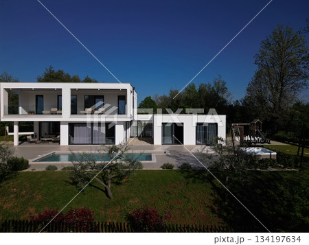 Modern luxury villa with pool, terraces, and clean minimalist architecture captured by drone. Bright sunny day, surrounding greenery, and contemporary outdoor living areas Modern luxury villa with pool, terraces, and clean minimalist architecture captured by drone. Bright sunny day, surrounding greenery, and contemporary outdoor living areas 134197634